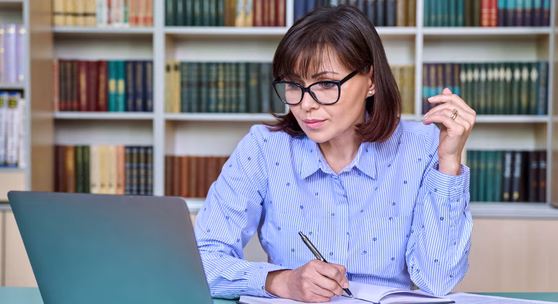 Lehrerin arbeitet konzentriert am Laptop im Master Pädagogik Fernstudium und lernt online.
