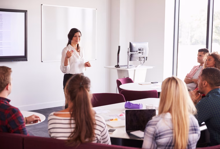 studierende sitzen in einem seminarraum und hören einer dozentin zu – symbolbild für das paeddr pädagogik doktorat im fernstudium und berufsbegleitendes pädagogikstudium